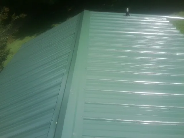 New green metal panels meeting at the ridge of a roof — Flat Roof Repair work by our crew in Dazey