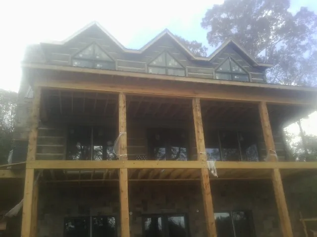 Dormers and porch framing on a large log home under construction — Roof Coating work by our crew in Dazey