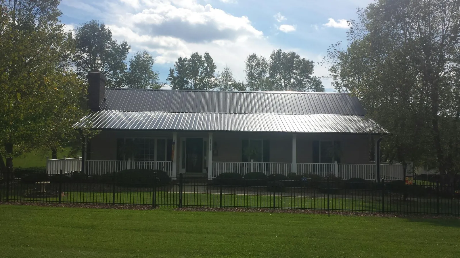 Gray metal roof on a brick ranch with a full width front porch — Gutter Guard Installation work by our crew in Dazey