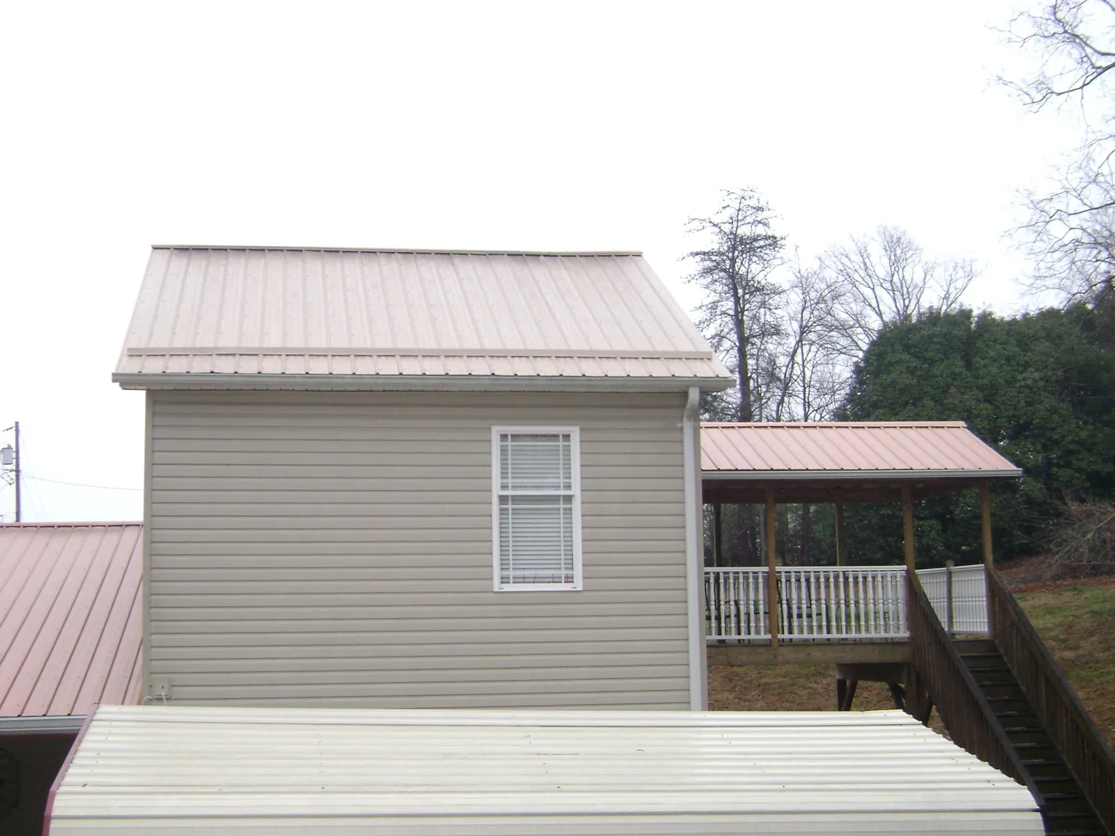 Tan metal roofs on a two story addition and attached porch, from a Roof Replacement job in Dazey