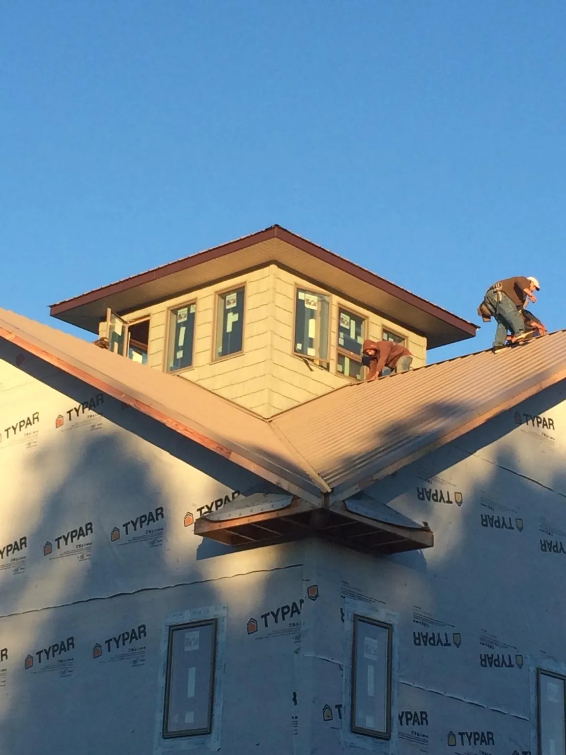 Roofers working around a rooftop cupola on a new metal roof at sunset — Roof Waterproofing in Dazey by Roofing Brothers